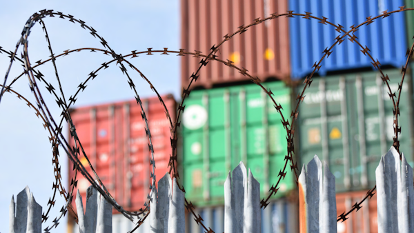 Barbed wire in front of shipping containers.